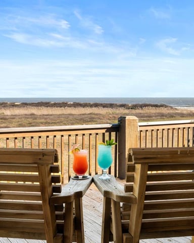 White Adirondack chair on beach deck with wine bottle and glasses overlooking ocean