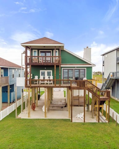 Covered deck with wicker seating, water view, trees, and metal railing overlooking pool and lake